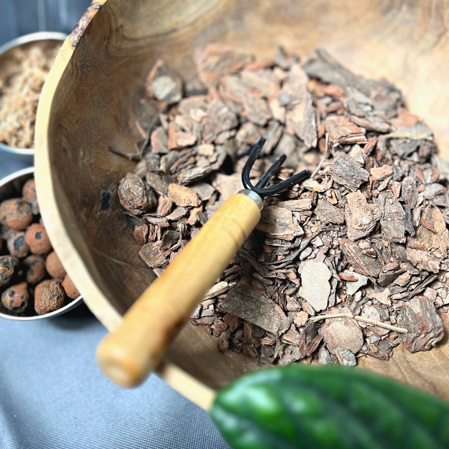 A pile of brown bark nuggets beside a bowl with Canadian long-fibered sphagnum moss and leca.