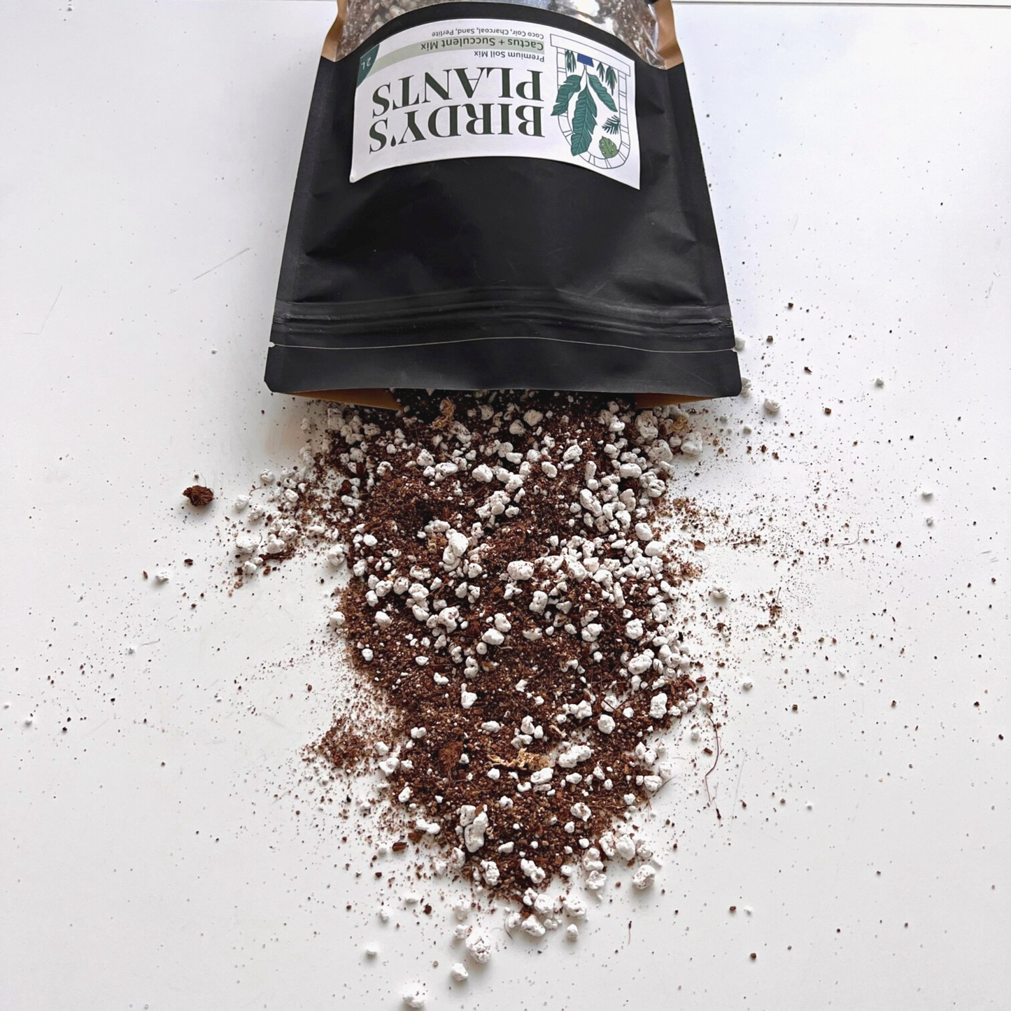 A bag of Birdy's Plants 2L Premium Cactus + Succulent Soil Mix being spilled out .