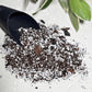 Soil scoop pouring potting mix with Hoya plant in background, mess-free tool for indoor plant repotting and soil mixing