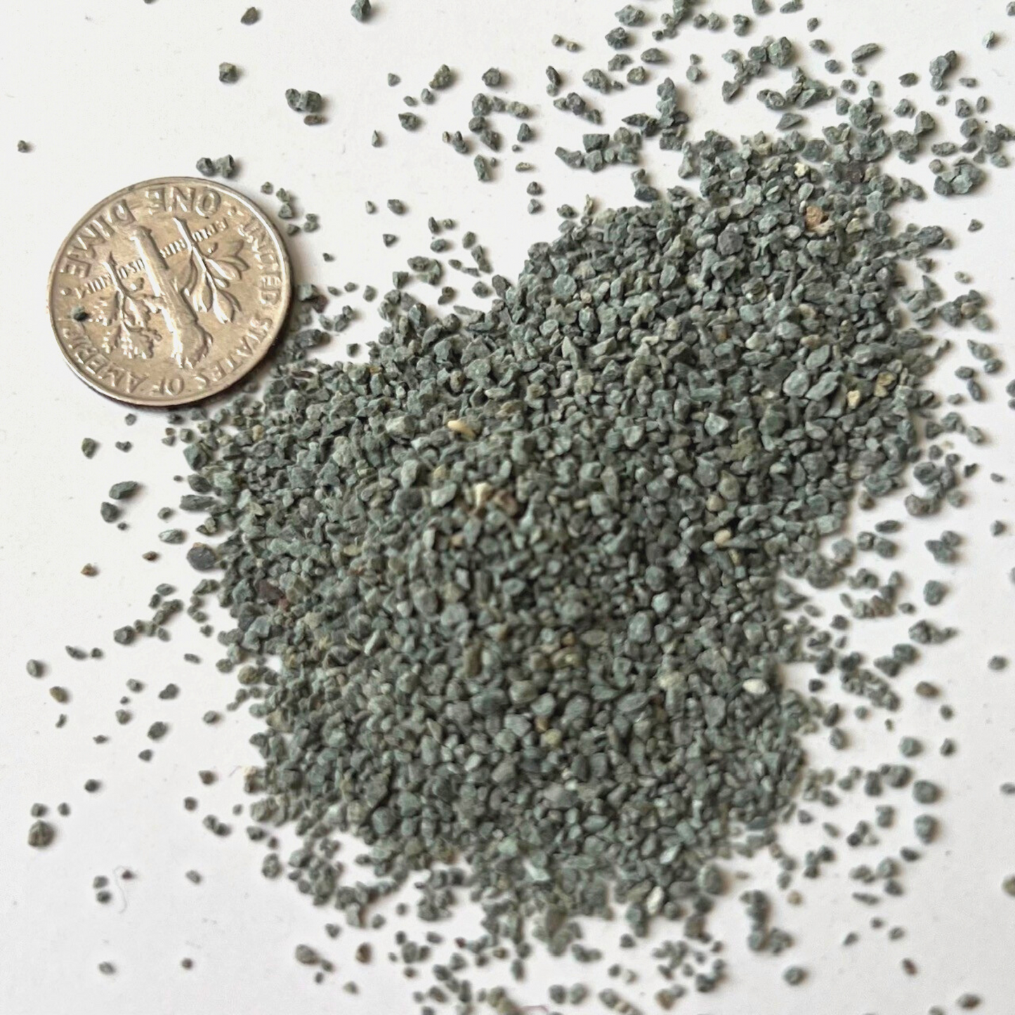 A pile of zeolite granules beside a 10 cent coin to show the various granule sizes.